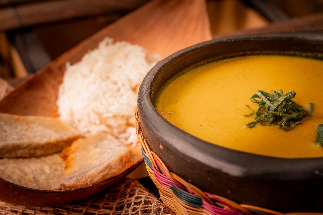 Sopa del Pacífico servida en olla de barro con patacones